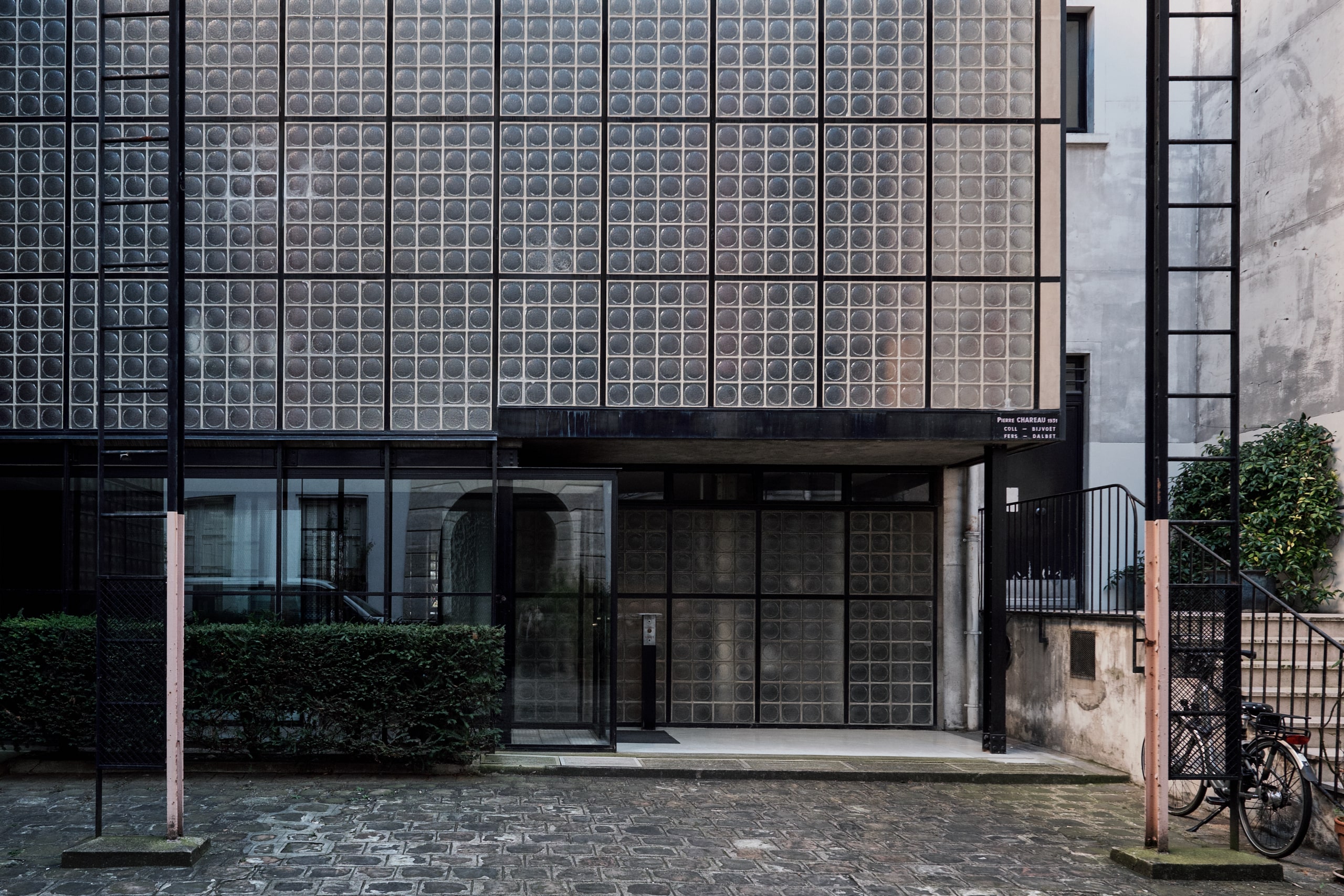 Blick auf die Eingangstüre und die Fassade eines Hauses aus Glasbausteinen. Pierre Chareau, Maison de Verre, Paris, Foto: August Fischer, CC BY-ND 2.0, via flickr