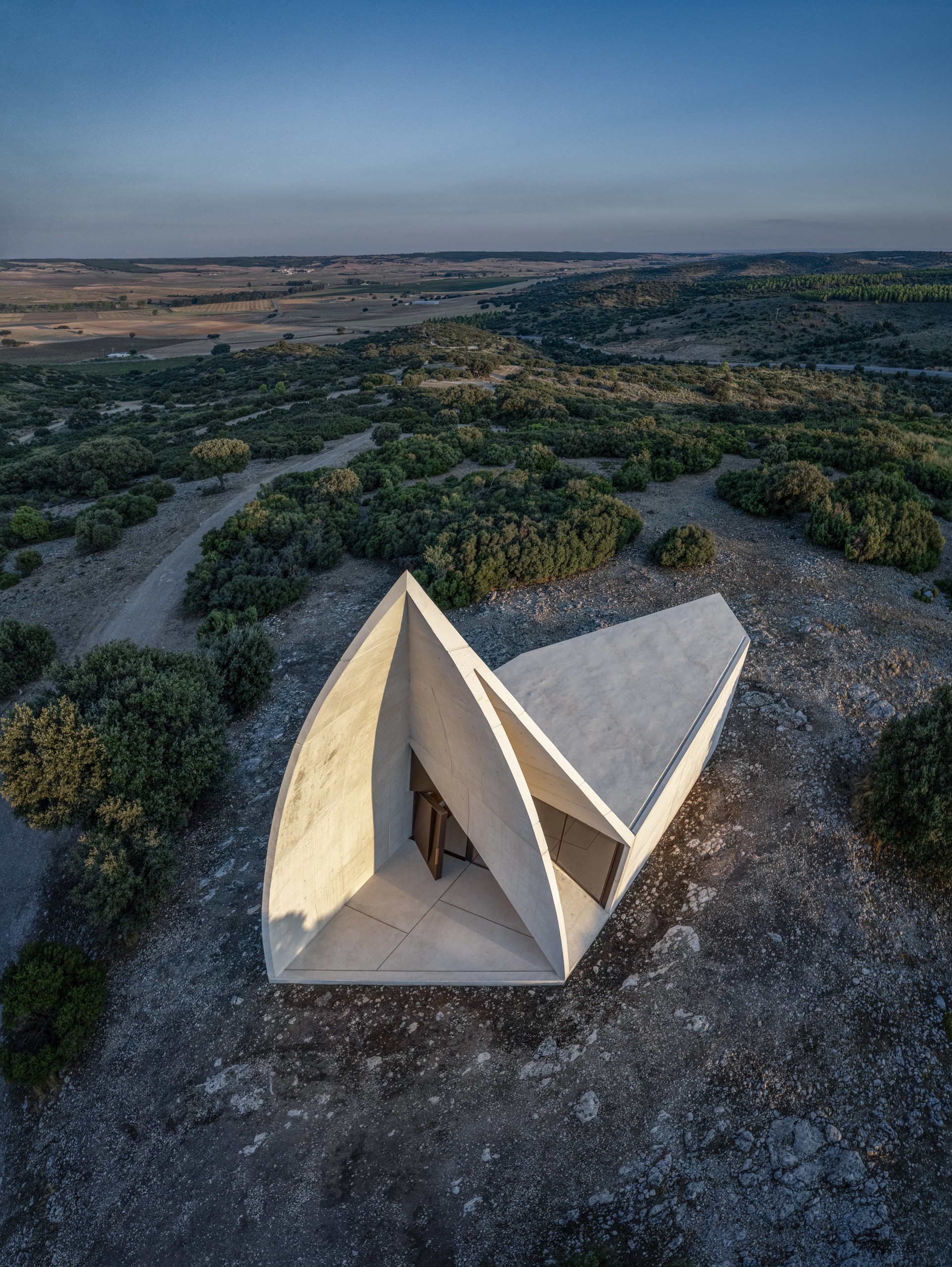 Blick aus der Vogelperspektive auf eine Kapelle aus hellem Beton, die an Origami erinnert. Kapelle in Cuenca, Sancho-Madridejos Architecture Office, Foto: Hisao Suzuki