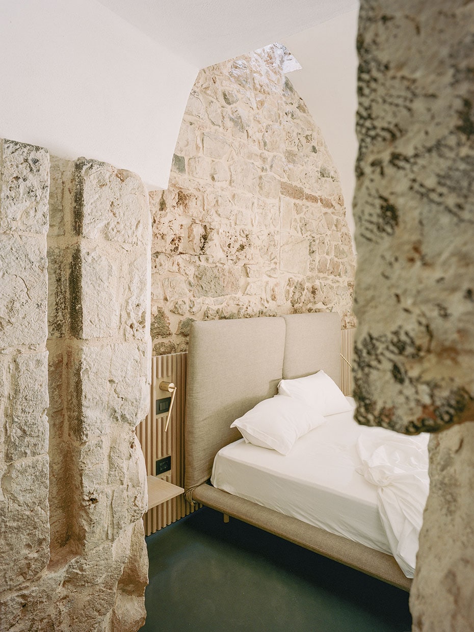 Blick in ein Schlafzimmer mit gemauerten und weißen Wänden. Valari, Masseria Belvedere, Carovigno, Foto: ©Lorenzo Zandri