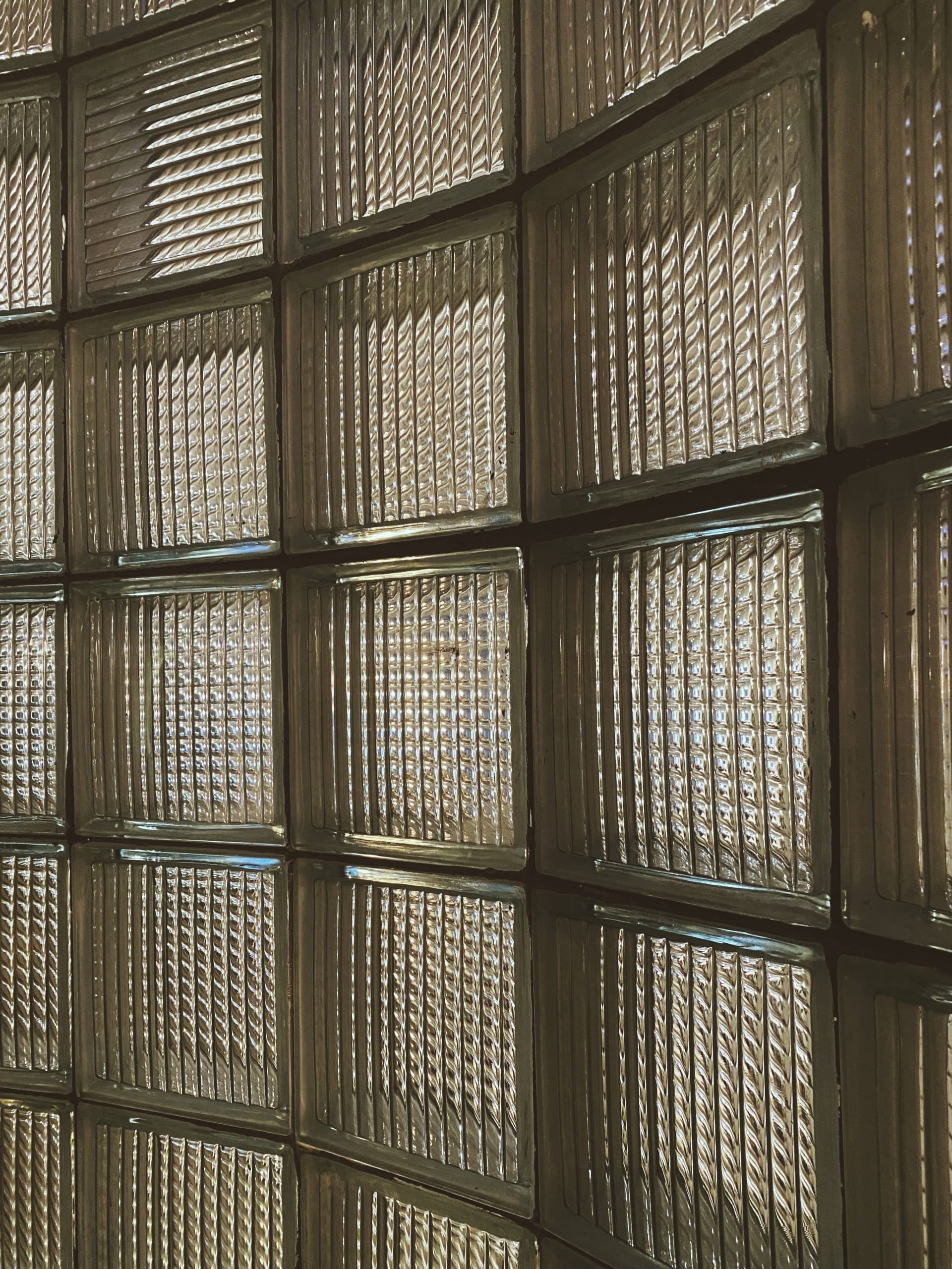 eine leicht gerundete Wand, die vollständig aus quadratsichen Glasbausteinen besteht. Foto: Anh Tuan To via Unsplash