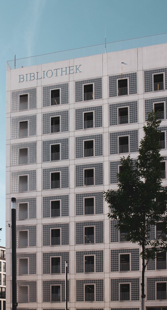Blick auf die Fassade eines Gebäudes mit gerasterter Fassade, dessen Flächen mit Glasbausteinen gefüllt sind. Stadtbibliothek Stuttgart, Foto: Marcel Strauß on Unsplash