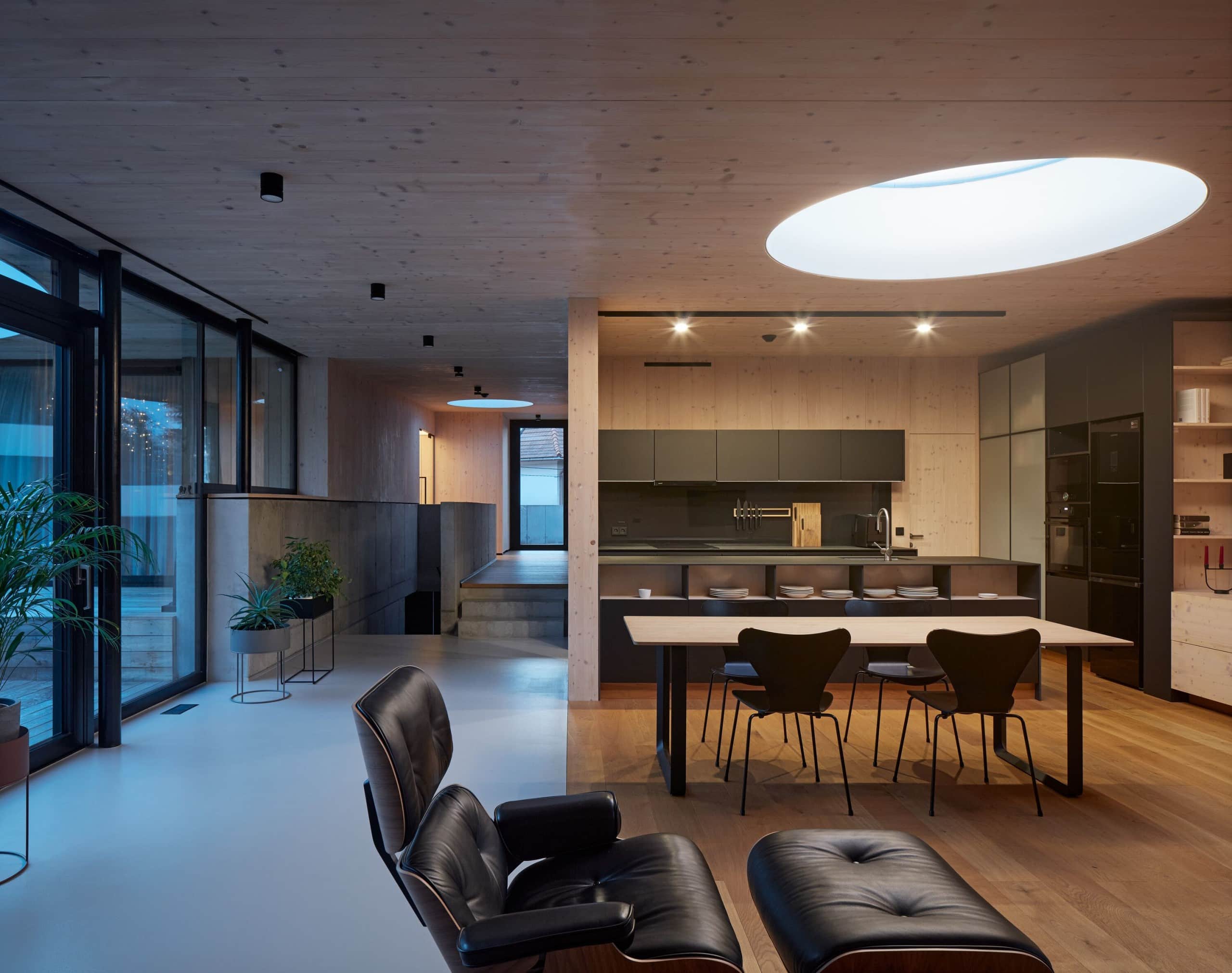 Wohnraum: Fensterfront, Essbereich mit Küche und Tisch, sessel, Treppen, große, runde Lampe