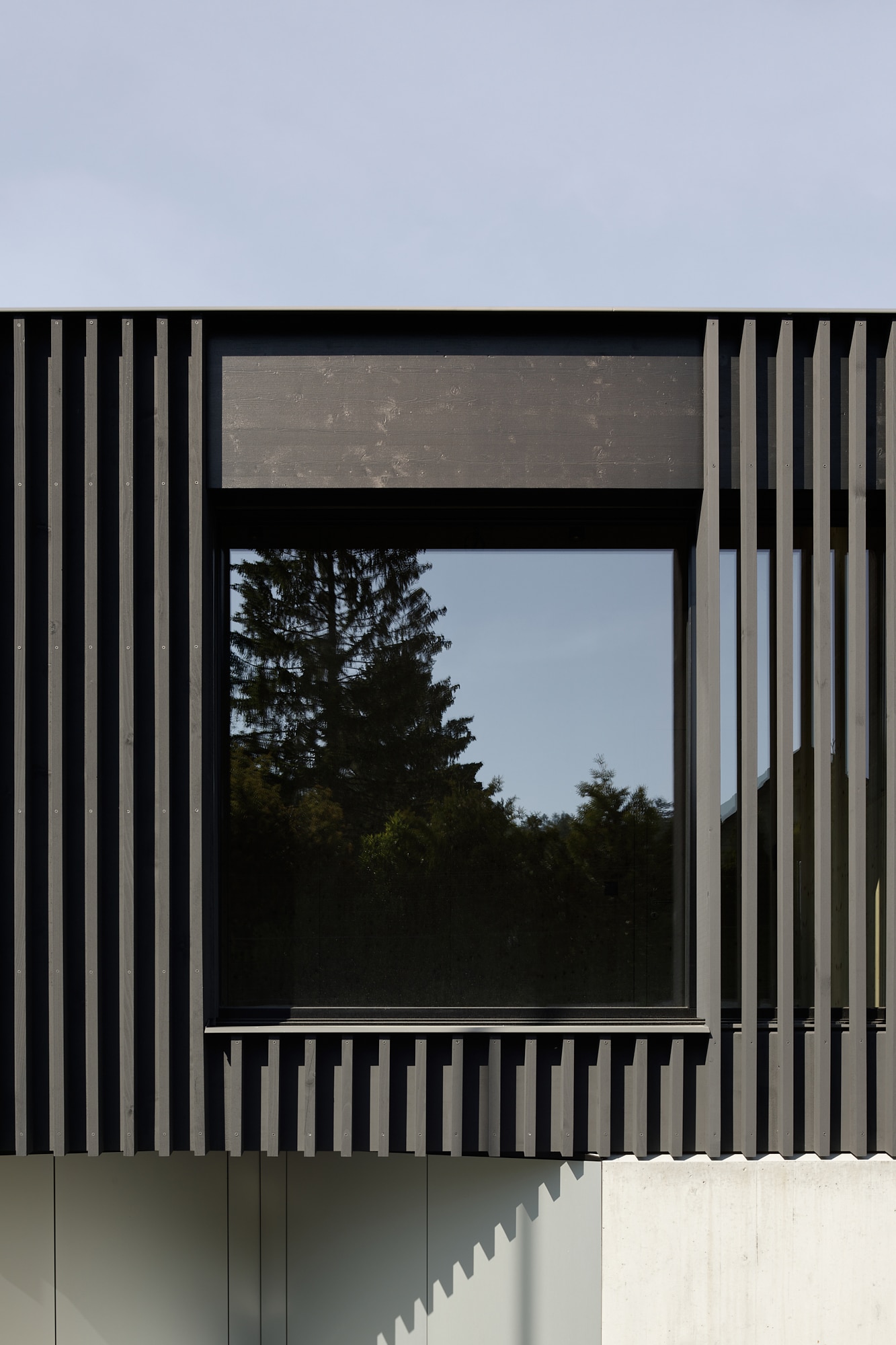 Große, schwarz verglaste Fensterflächen passen sich unauffällig in die Holzkonstruktion des Obergeschosses an und sorgen für mehr Privatsphäre. Foto: © Gautschi Lenzin Schenker